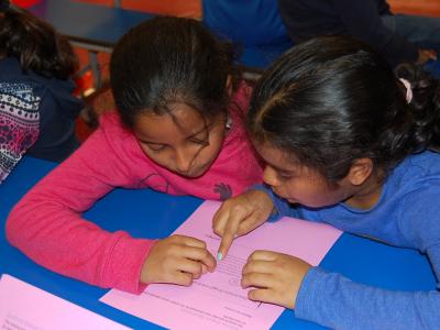 Two girls working together to read a passage.